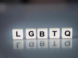 wording LGBTQ text in plastic English letters are stamped onto a plastic sheet reflected on the glass table photo
