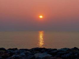 sunrise above sea at rock beach photo