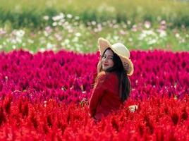 sonrisa feliz mujer asiática en el colorido jardín de flores rojo celosia foto