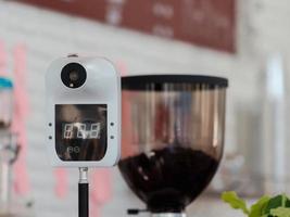 digital machine for measuring body temperature by placing hand or forehead over the sensor in coffee cafe photo