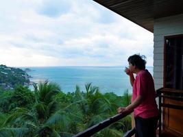 man drinking morning coffee at sea view terrace photo