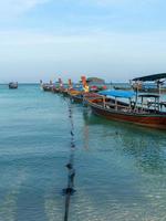 wooden longtail boats paring on blue sea with anchor's rope at Lipe Island photo