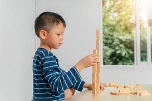 niño jugando con bloques de madera en casa foto