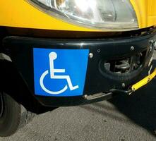 símbolo de silla de ruedas azul o signo en el parachoques del autobús escolar amarillo foto