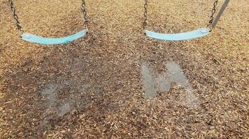 blue seat on swing with water puddle and mulch photo