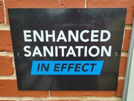 enhanced sanitation in effect sign on brick wall photo