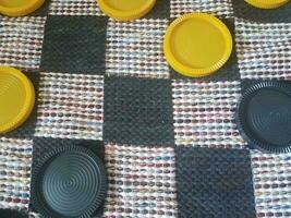 black and yellow plastic checkers on fabric board photo