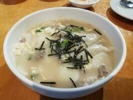 Korean soup with dumplings and seaweed on table photo