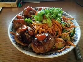 Korean meatballs and carrots in bowl on wood desk photo