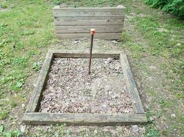 horseshoe pit with metal pole and wood backstop photo