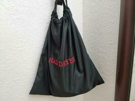 black fabric hair dryer bag on hotel wall with red text photo