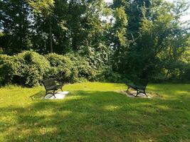 two black metal benches in the grass photo