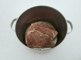 beef steak with seasoning and liquid in metal pot on snow photo