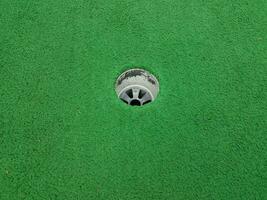 hole on miniature golf course with green artificial grass photo