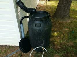 black plastic rain barrel installed on a house photo