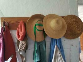 sombreros de paja colgados en clavijas de madera en la pared blanca foto