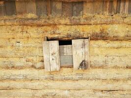 boarded window on old log and mud cabin photo