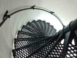 black iron metal spiral staircase and white wall in lighthouse photo