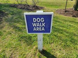 blue dog walk area sign on grass or lawn photo