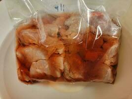 red bloody meat thawing in a plastic bag in water photo