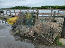 pile of metal lobster traps on dock near water photo