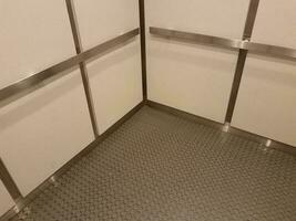 interior of elevator with grey floor and metal bars and white walls photo