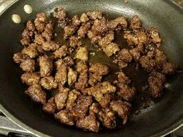 carne molida cocinando en sartén con aceite foto