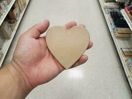 hand holding a wood heart in an aisle photo