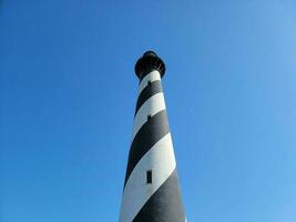 tall black and white striped lighthouse building with blue sky photo