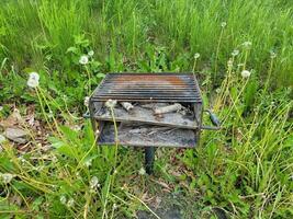 old barbecue grill with ashes and green weeds photo