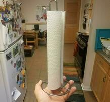 hand holding paper towels in kitchen near refrigerator photo