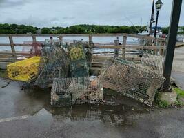 pile of metal lobster traps on dock near water photo