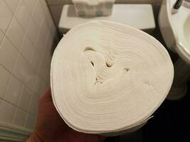 hand holding toilet paper roll without center over toilet photo