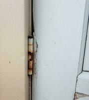 old metal hinge with rust on white door photo