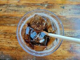 paper straw in glass of soda with ice on table photo