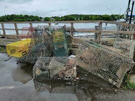 pile of metal lobster traps on dock near water photo