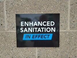 enhanced sanitation in effect sign on brick wall photo