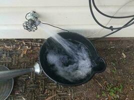 black plastic bucket being filled with water from a spigot photo