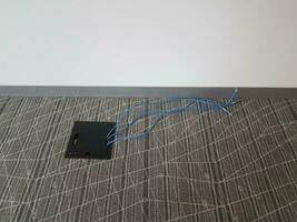 black access panel in grey carpet with blue cables photo
