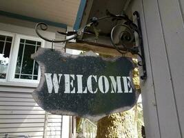 weathered black metal welcome sign hanging on wall photo