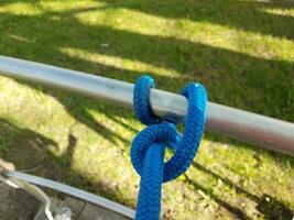 blue rope or cord tied to metal pole and green grass photo
