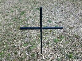 cruz negra en césped o patio con piedras foto