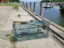 trampa para langostas o jaula en el muelle con agua y botes foto