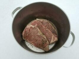 beef steak with seasoning and liquid in metal pot on snow photo