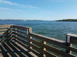 plastic fishing rod holder on wood railing with water photo