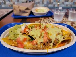 Mexican nachos on plate with avocado and salsa and cheese photo