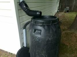 black plastic rain barrel installed on a house photo