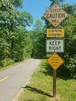 asphalt bike path with steep hill and caution signs photo