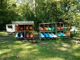 wooden rack with colorful kayaks and green grass photo