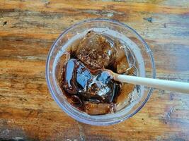 paper straw in glass of soda with ice on table photo